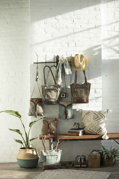 a white brick wall with several purses and hats hanging on it's side