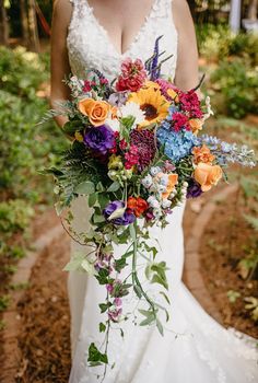 a woman in a wedding dress holding a colorful bouquet