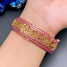 Give your wrist a royal touch with this exquisite Jadau Bangle. Expertly crafted from sterling silver with lustrous gold plating, it boasts a stunning array of ruby-like red stones. The intricate design features an openable screw, allowing you to effortlessly slip it on and off. Elevate your style with this timeless piece of luxury. Ruby Bangles Gold, 22k Gold Jewelry Necklaces, Ruby Bangles, Black Beads Mangalsutra, Black Beads Mangalsutra Design, Mangalsutra Designs, 22k Gold Jewelry, Pearl Necklace Set, Bangles Jewelry Designs