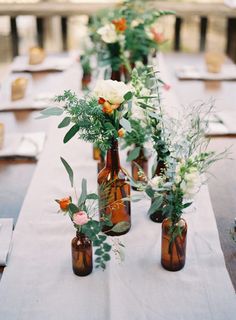 there are many bottles with flowers in them on the table