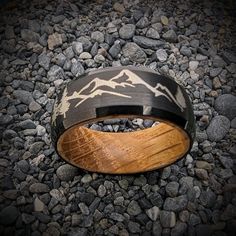 a wooden ring with mountains on it sitting on some rocks in the middle of nowhere