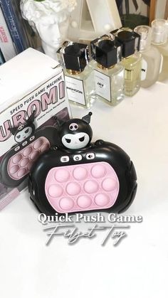 a black and pink purse sitting on top of a table next to some perfume bottles