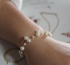 a close up of a person's arm wearing a bracelet with pearls