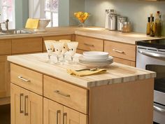 a kitchen island with plates and glasses on it in front of an oven, sink and dishwasher