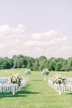 an outdoor ceremony setup with white chairs and flowers