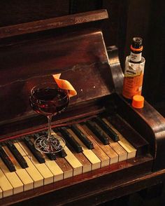 a glass of wine sitting on top of an old piano