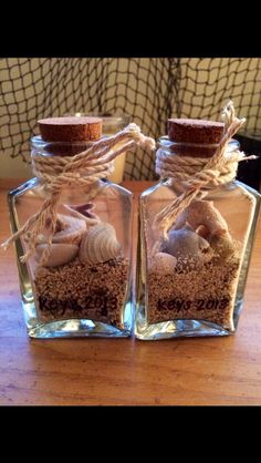 two glass bottles filled with sand and shells