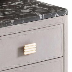 a grey and black marble top desk with two drawers on each side, one drawer has gold handles