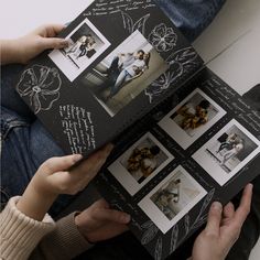 two people holding an open book with pictures on it