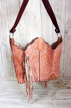 Bucket Bag Cowboy Boot Fringe PurseHand-cut FringeHand-Crafted from a Pair of BootsNo Two AlikeLeather Body/Leather strapWestern conchoSolid BaseMagnetic ClosureMeasures approx. 10”x13”FAQ'sReviews Best Cowboy Boots, Boot Purse, Totes Boots, Cowboy Boot Purse, Hipster Purse, Custom Cowboy Boots, Handmade Leather Purse, Western Handbags, Handpainted Bags