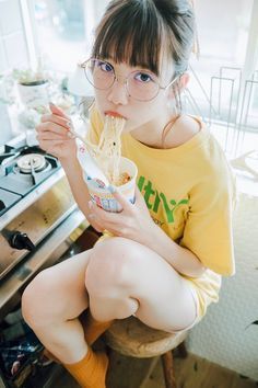 a woman sitting on top of a chair eating something out of a cup in front of her