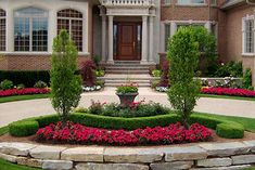 a large house with flowers and bushes in the front yard