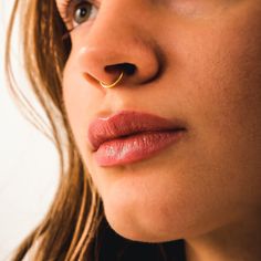 a close up of a woman's nose with a gold nose ring on it