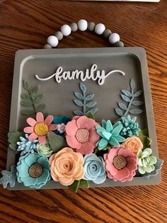 a wooden table topped with a gray tray filled with flowers and the word family written on it