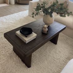 a coffee table with a book, vase and candle on it in a living room