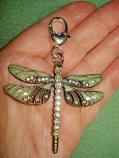 a hand holding a key chain with a dragonfly on it