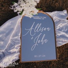 a blue sign with white flowers on it sitting on the ground next to a wedding dress