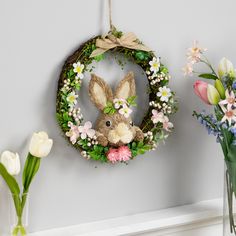 a wreath and flowers are hanging on the wall next to a bunny head with a bow