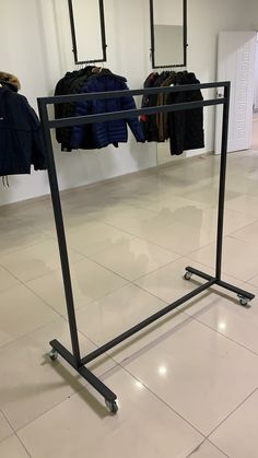 an empty clothing rack with clothes hanging on the wall and in front of it is a white tiled floor