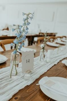 the table is set with white plates and place settings for guests to sit down at