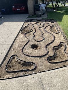 a garden design made out of dirt on the side of a road in front of a house