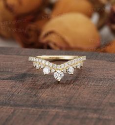 a gold ring with three diamonds sitting on top of a wooden table next to some fruit