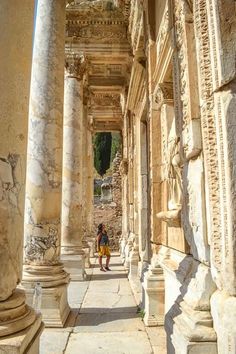 a person is standing in an old building with columns and stone work on the walls