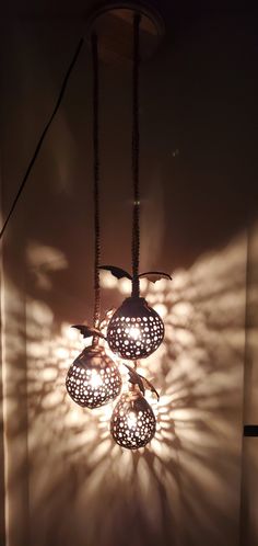 three lights are shining on the wall in front of a shadow cast by a light fixture