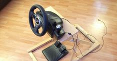 a steering wheel on top of a wooden table with a remote control attached to it