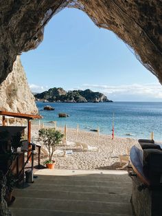 an open air cave with stairs leading to the beach