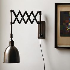 a wall mounted light next to a painting on the wall with a lamp hanging from it's side