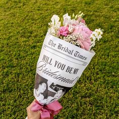 a person holding a bouquet of flowers on top of a lush green grass covered field