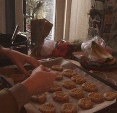 a person is baking cookies on a pan in front of an open window with curtains