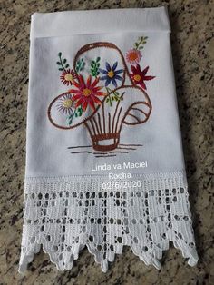 a white doily with flowers on it sitting on a counter top next to a piece of cloth