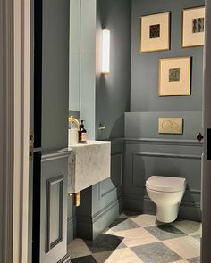 a white toilet sitting in a bathroom next to a wall mounted light above it's tank