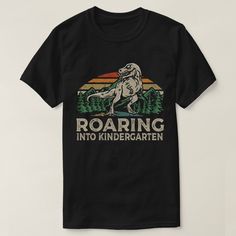 a black t - shirt with an image of a dinosaur roaring into the wilderness on it