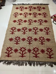 an old rug with red flowers and fringes is on the floor next to other items