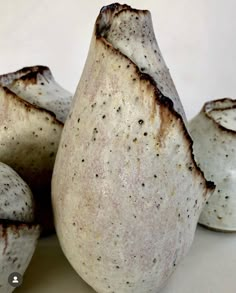 three white vases sitting next to each other on top of a table with brown speckles