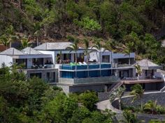 an aerial view of a house surrounded by trees and greenery on a hill side