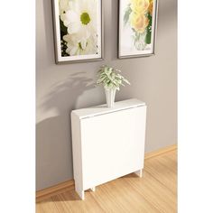 two framed pictures hang on the wall above a white cabinet and vase with flowers in it