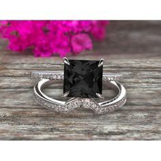 a black and white diamond ring on top of a wooden table with flowers in the background