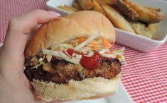 a person is holding a hamburger and french fries in front of the meal on the table