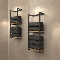 two black towels are hanging on the wall next to shelves with folded gray towels in them