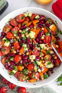 a white bowl filled with beans, tomatoes and cucumbers