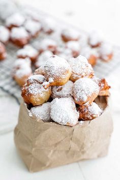 powdered sugar covered donuts in a brown paper bag on a white counter top