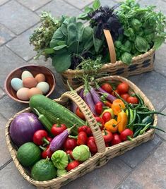 two baskets filled with vegetables sitting on top of a stone floor next to each other