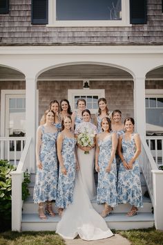 a group of women standing next to each other in front of a house