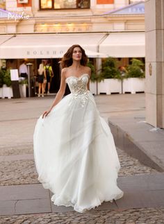 a woman in a wedding dress is walking down the street with her hand on her hip