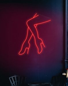 a neon sign that is on the side of a wall next to a chair and table