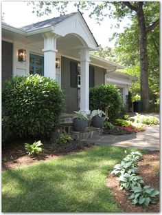 a house with bushes and flowers in front of it